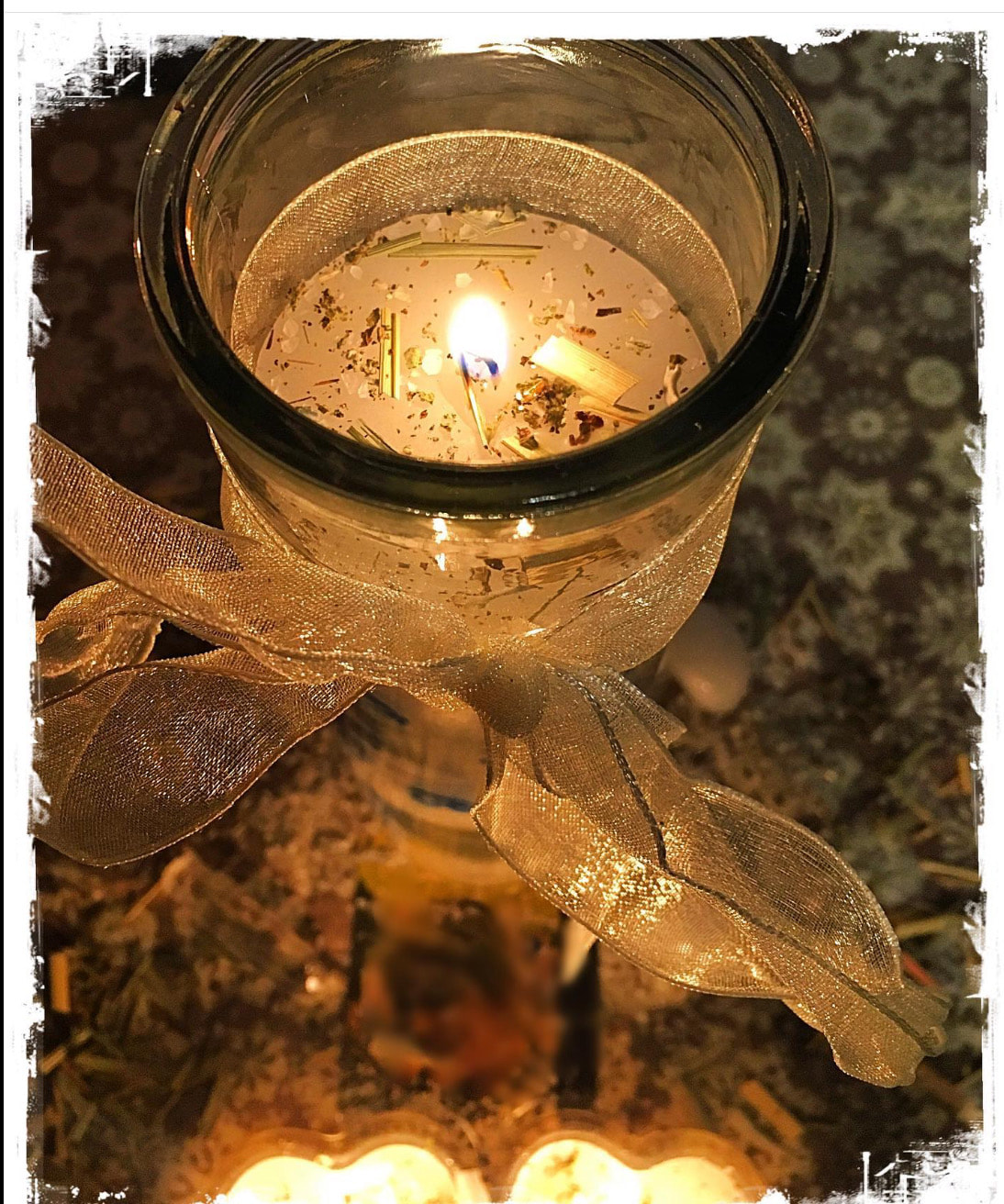 peaceful glass candle with herbs and golden ribbon tied around it