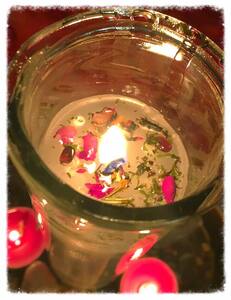 rose petals scattered around a lit white candle to heal a broken heart